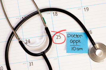 a stethoscope over a calendar with a post it note saying "doctor appointment 10am"