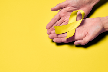 Picture of hands holding a yellow ribbon to represent world suicide prevention day.