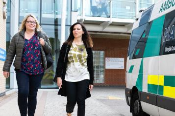 Two women walking next to an ambulance
