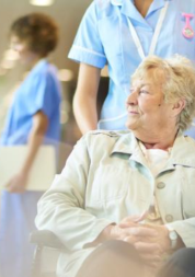 A nurse assisting a patient in a wheelchair in the hospital